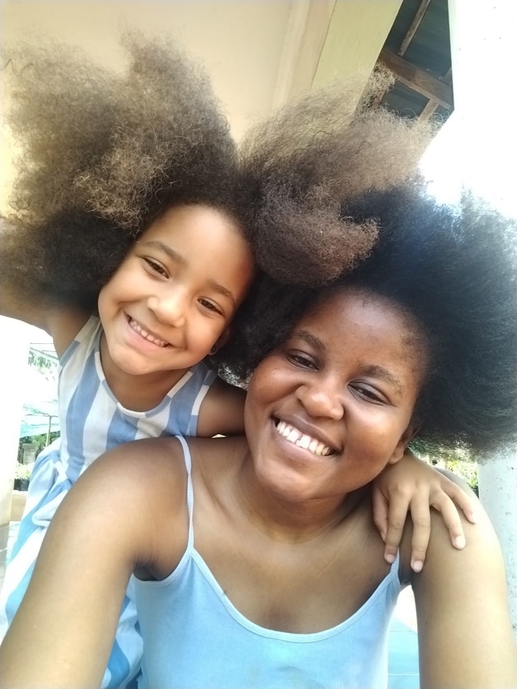 A mother and daughter smiling with their natural hair
